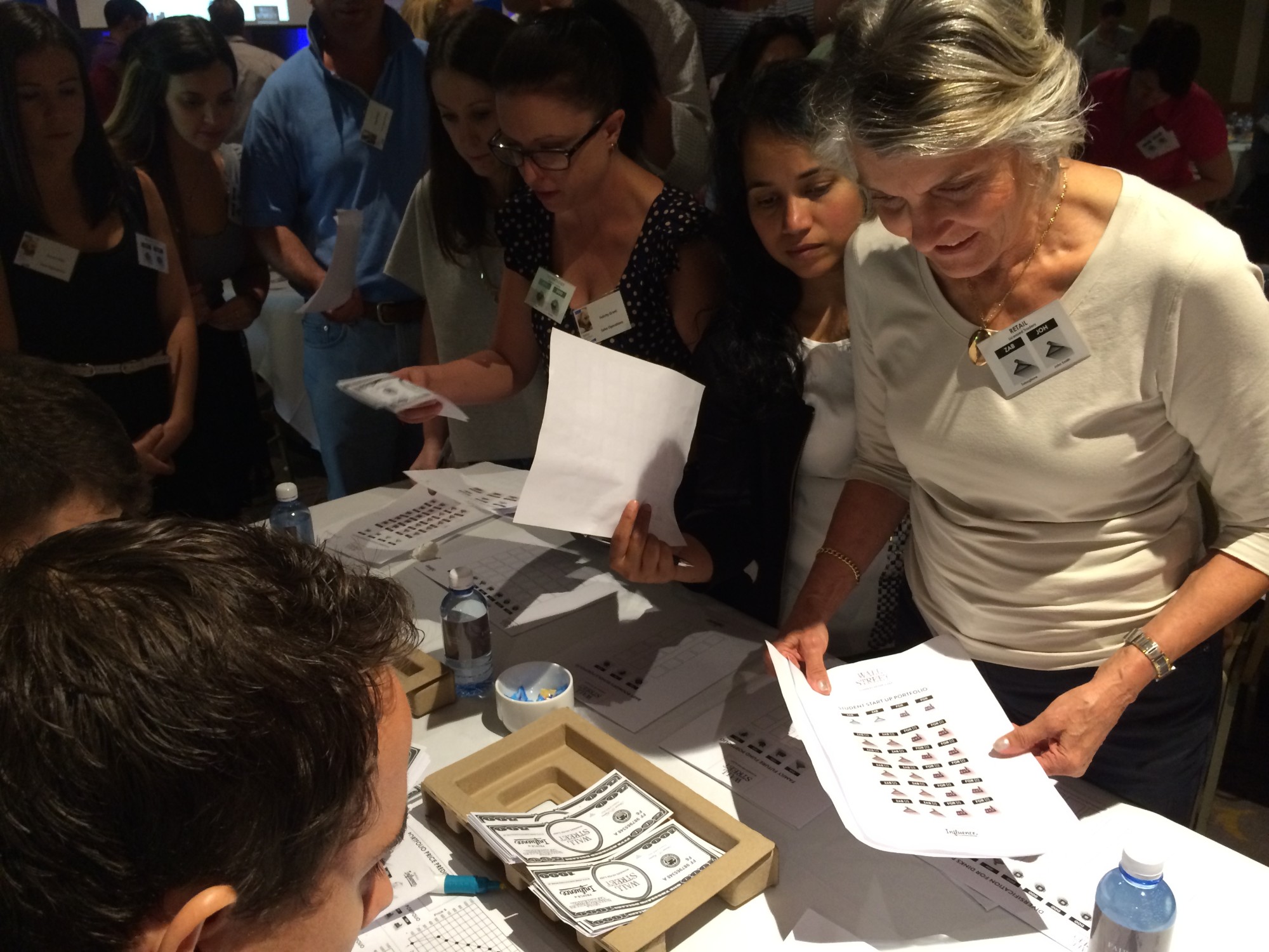 Traders crowding a table to check prices and swap shares during Wall Street
